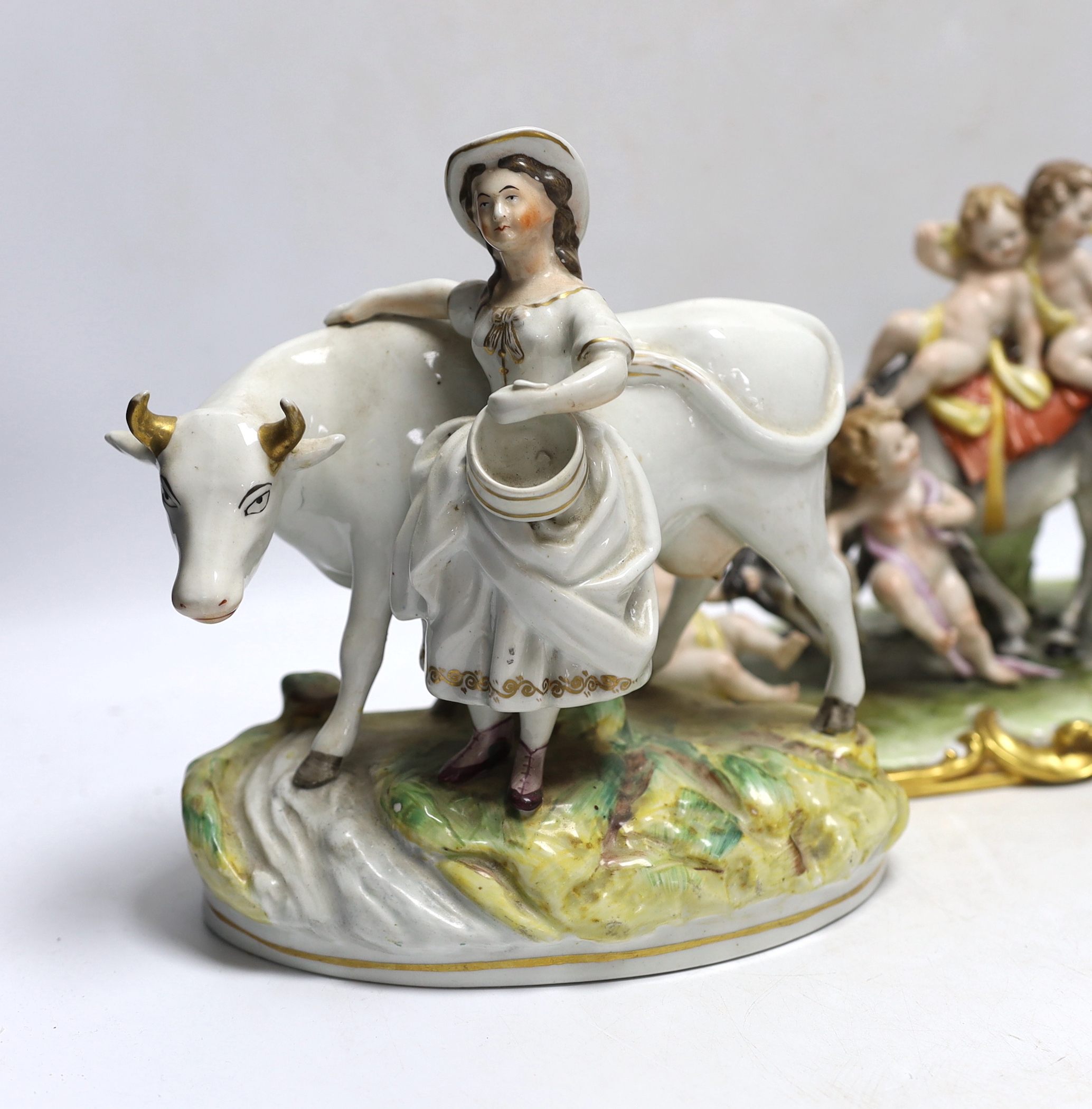 A pair of 19th century Staffordshire cow groups and an Italian donkey and cherub group, tallest 20.5cm